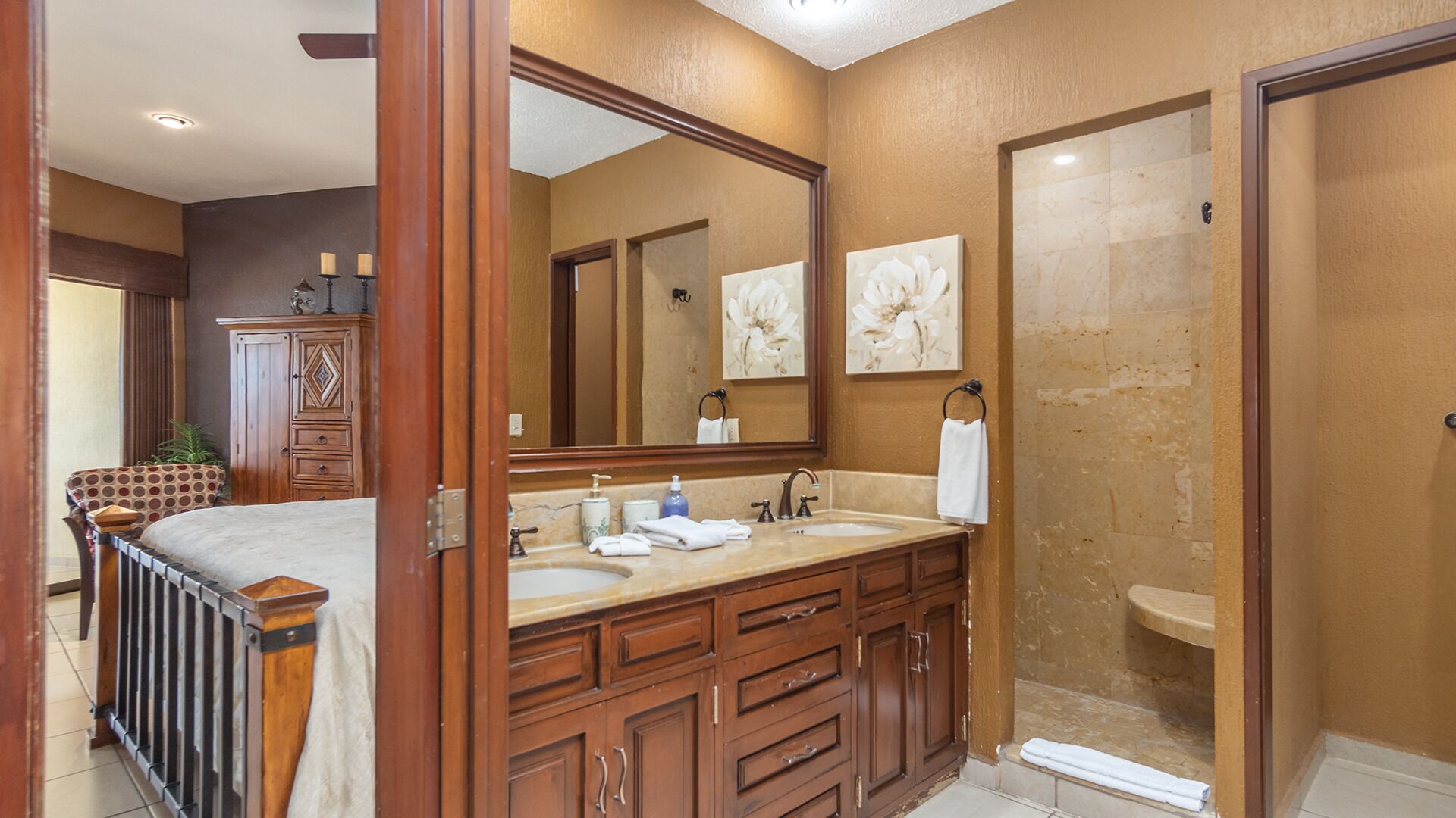 A bathroom with a double sink vanity, a large mirror, and a shower area.