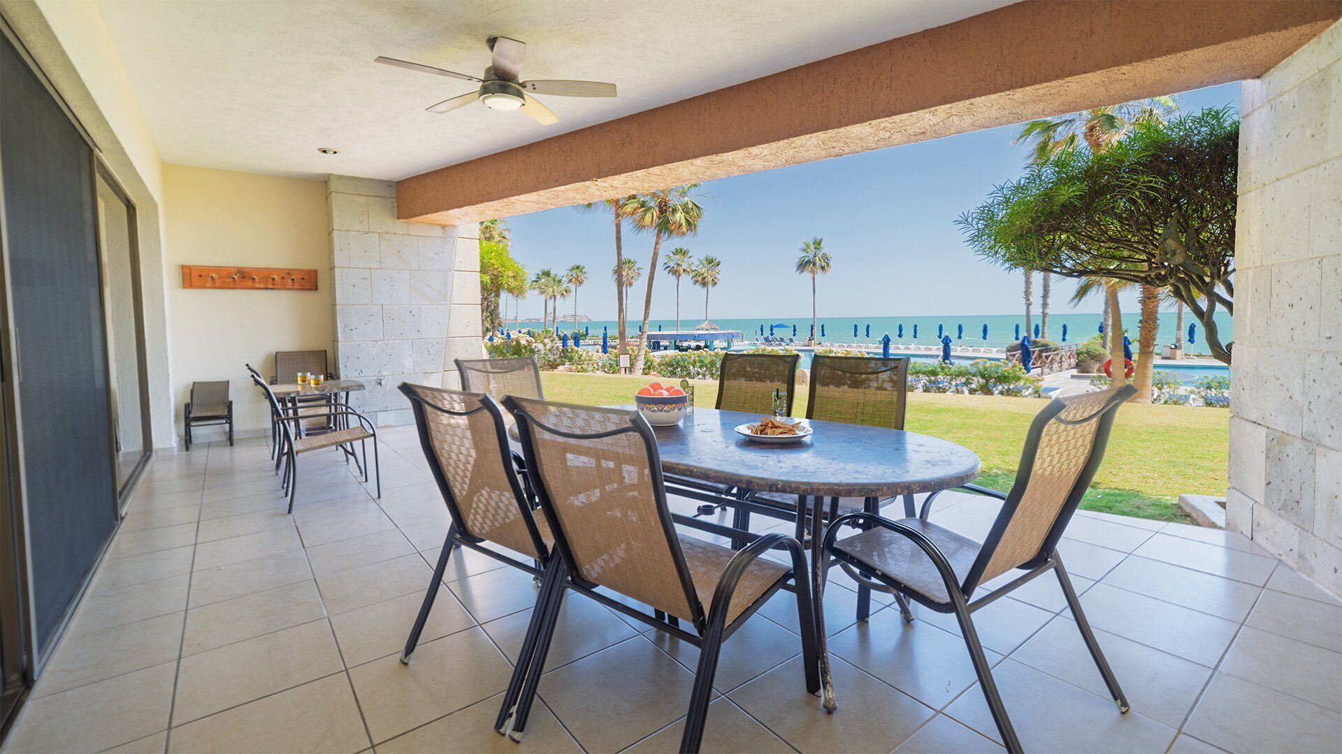 A covered outdoor dining area with a view of the beach and ocean.