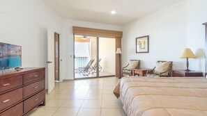 Une chambre d’hôtel équipée d’un lit, d’une télévision, d’un bureau, de chaises, d’une lampe et offrant une vue sur la piscine grâce à une porte coulissante.