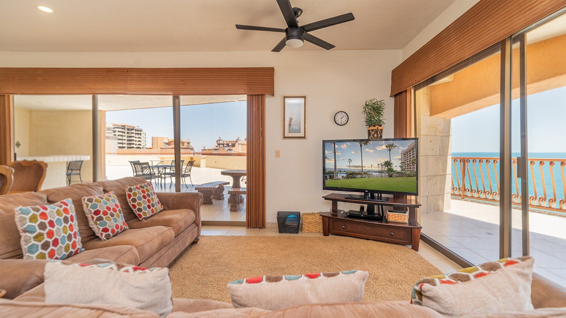 Ein Wohnzimmer mit Sofa, Fernseher und einem Balkon mit Meerblick.