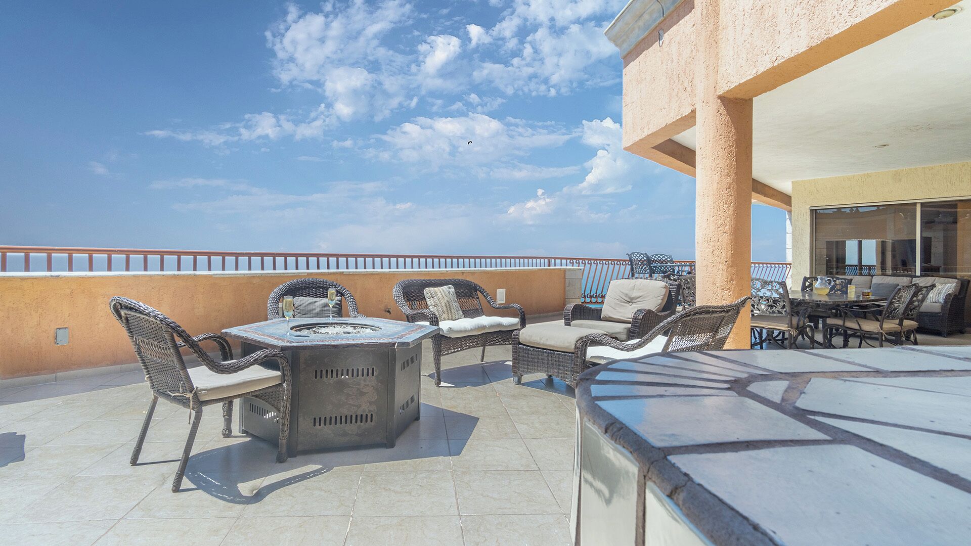 A rooftop terrace with outdoor furniture, a fire pit, and a view of the sea.