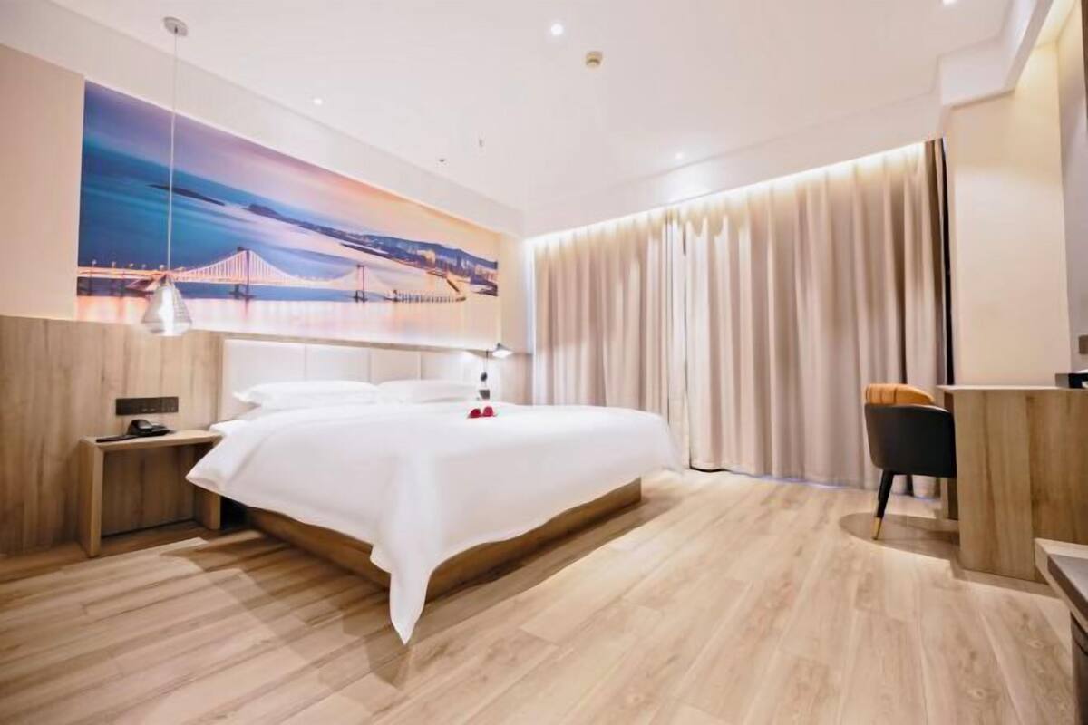 Une chambre d’hôtel moderne avec un grand lit, un bureau et une vue sur un pont.