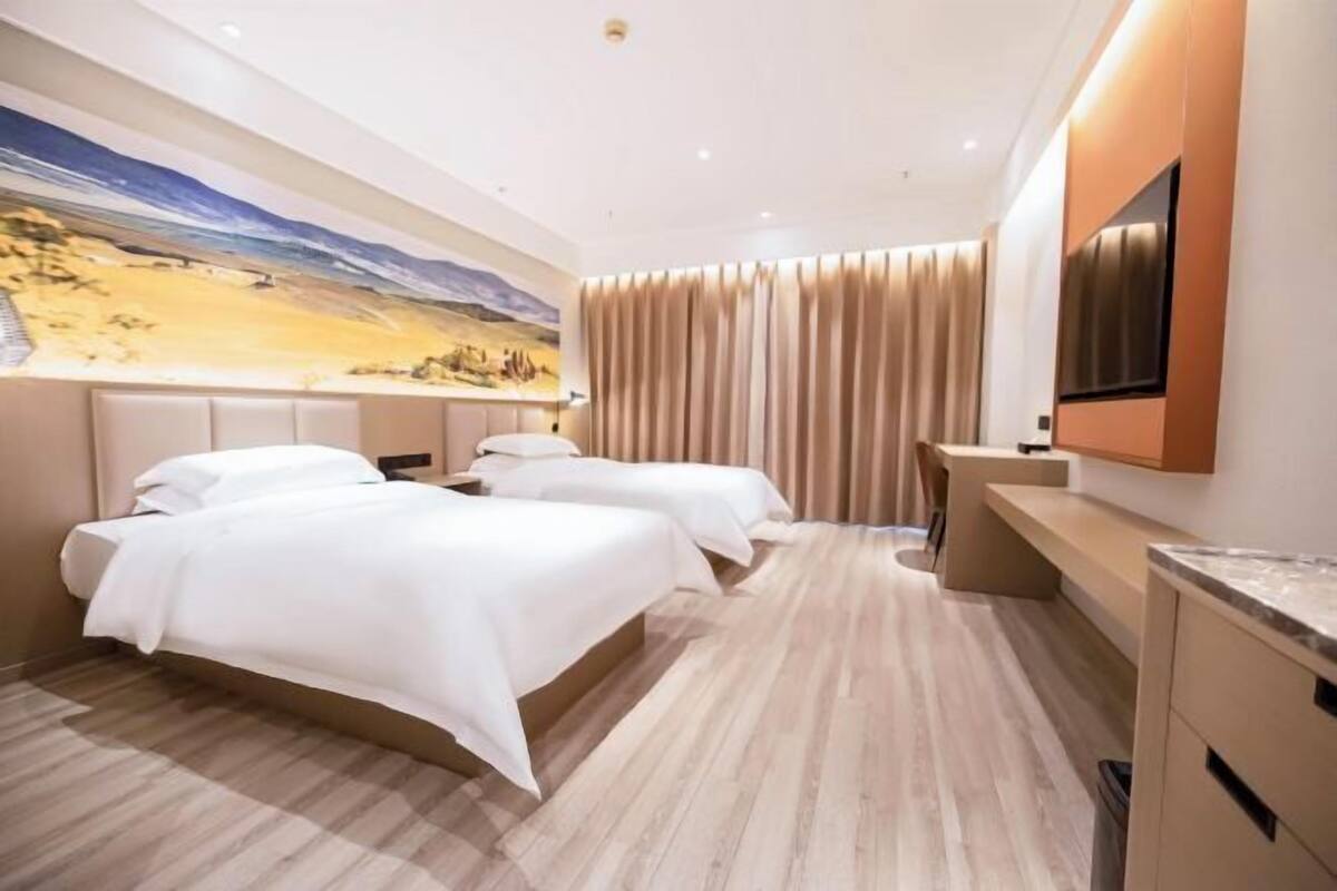 Une chambre d’hôtel avec deux lits, un bureau, une télévision et une fresque murale.