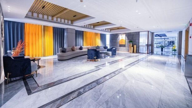 A modern lobby with a curved sofa, a coffee table, and a seating area with chairs. - Qingdao Likelai Garden Hotel (Chengyang Zhengyang Middle Road Metro Station) (Qingdao)