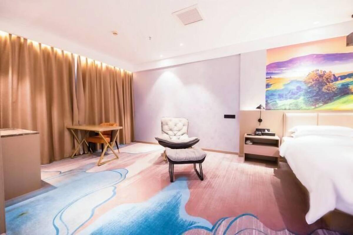 Une chambre d’hôtel avec un lit, une chaise, un bureau et un tableau au mur.