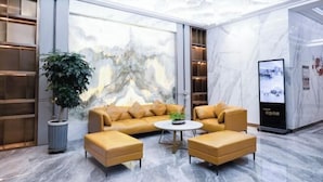 A modern lobby with a marble floor, a sofa set, a coffee table, and a large potted plant. - Qingdao Likelai Garden Hotel (Chengyang Zhengyang Middle Road Metro Station) (Qingdao)