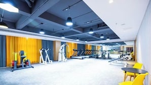 A gym with exercise equipment, a treadmill, and a weight bench. - Qingdao Likelai Garden Hotel (Chengyang Zhengyang Middle Road Metro Station) (Qingdao)