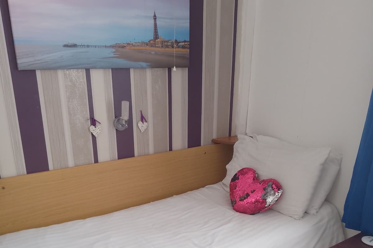 A hotel room with a bed, a striped armchair, a small table, and a painting on the wall.