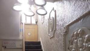 Eine Treppe mit Handlauf, einem 'HELLO'-Schild, einem 'STAFF ONLY'-Schild und einer Wand mit dekorativem Stuck.