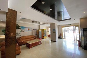 A spacious lobby with a high ceiling, a reception desk, and a seating area with a sofa and coffee table.