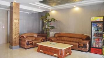 A lobby with a sectional sofa, a wooden coffee table, and a vending machine.