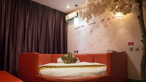 A room with a curved bed, a red chair, an air conditioning unit, and a wall decorated with heart shapes and flowers. - Gaocheng Dushi 118 Chain Hotel (Shijiazhuang)