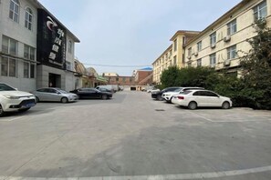 Um estacionamento com vários carros, edifícios com placas de sinalização e um céu claro.