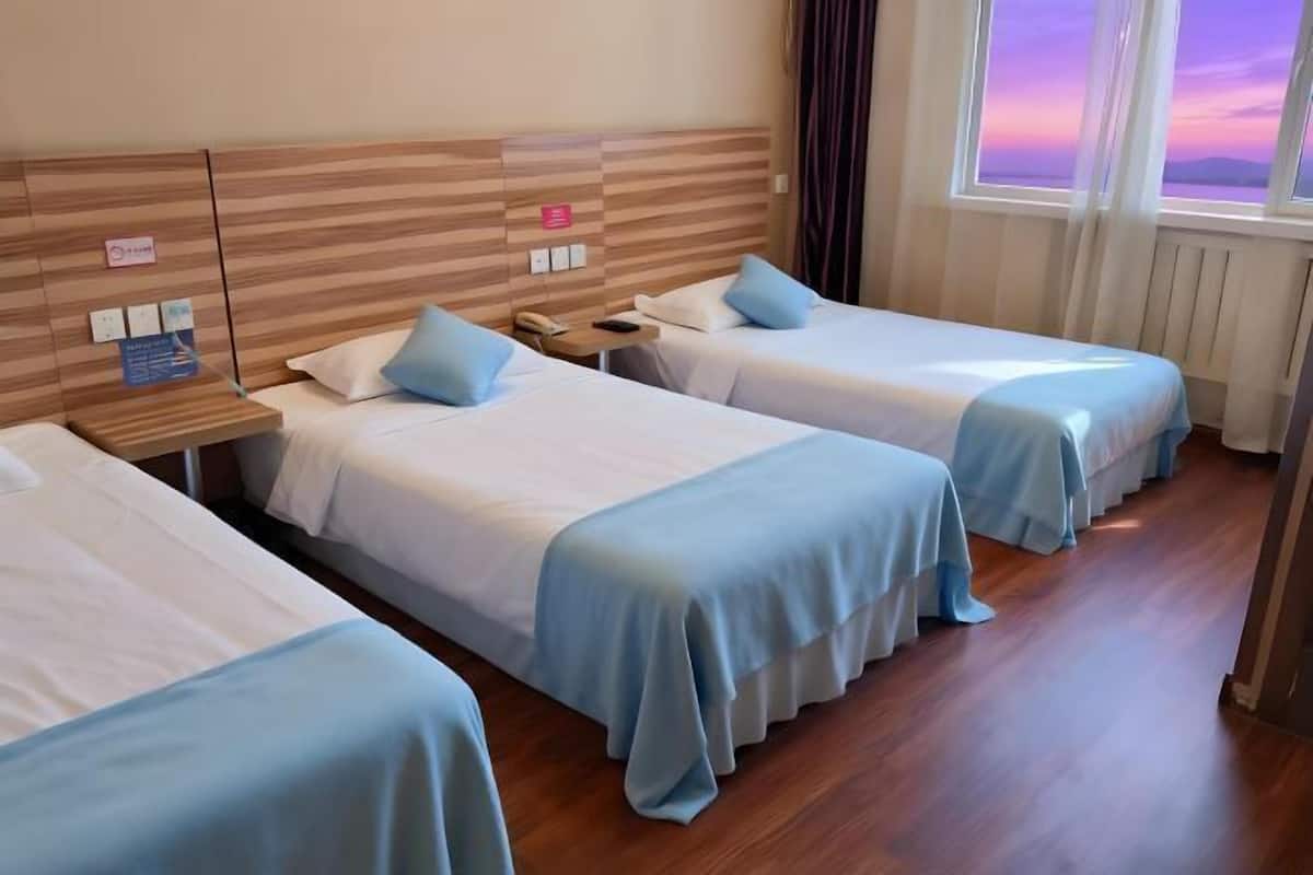 Une chambre d’hôtel avec deux lits, une tête de lit en bois, une table de chevet, une fenêtre donnant sur un paysage agréable et un panneau accroché au mur.