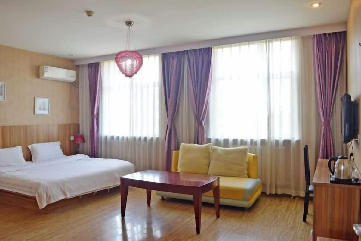 Une chambre d’hôtel avec un lit, un canapé, une table basse en bois et un téléviseur.