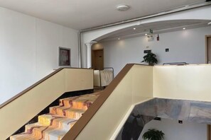 A staircase with a handrail and a landing area with a plant. - Gaocheng Dushi 118 Chain Hotel (Shijiazhuang)