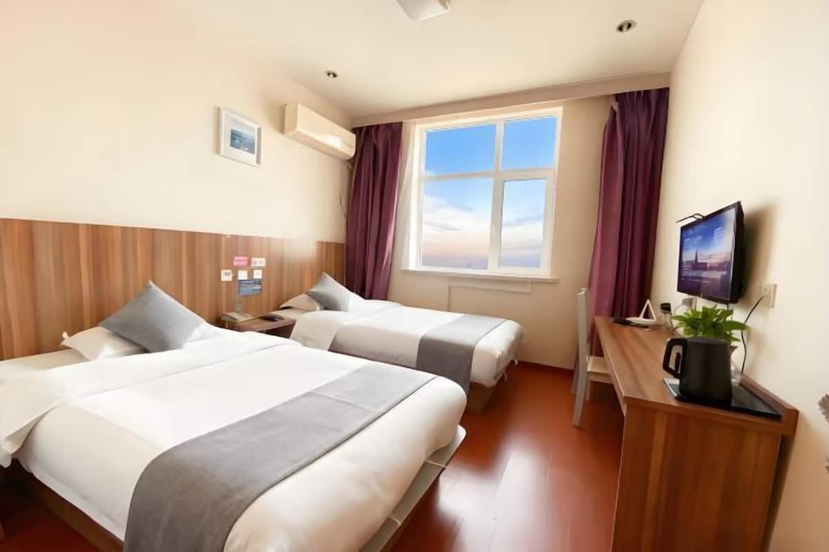 Une chambre d’hôtel avec deux lits, un bureau, une télévision et une fenêtre avec des rideaux.