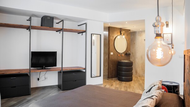 Ein modernes Schlafzimmer mit Bett, Fernseher, einer Holzablage und einer Wand aus alten Reifen.