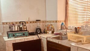 Een kleine keuken met een gasfornuis, een blender en een gasfles.