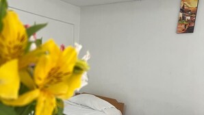Een hotelkamer met twee enkele bedden, een klein nachtkastje en een aan de muur bevestigde televisie.