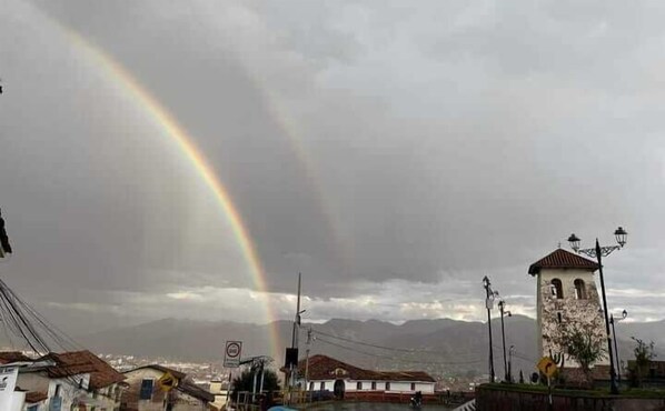 A building with a clock tower, a no parking sign, and a rainbow in the sky. - Enede Hostel Cusco (Cusco)