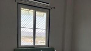 Un dormitorio con cama, ventana con vistas, aire acondicionado y una pequeña mesita de noche.