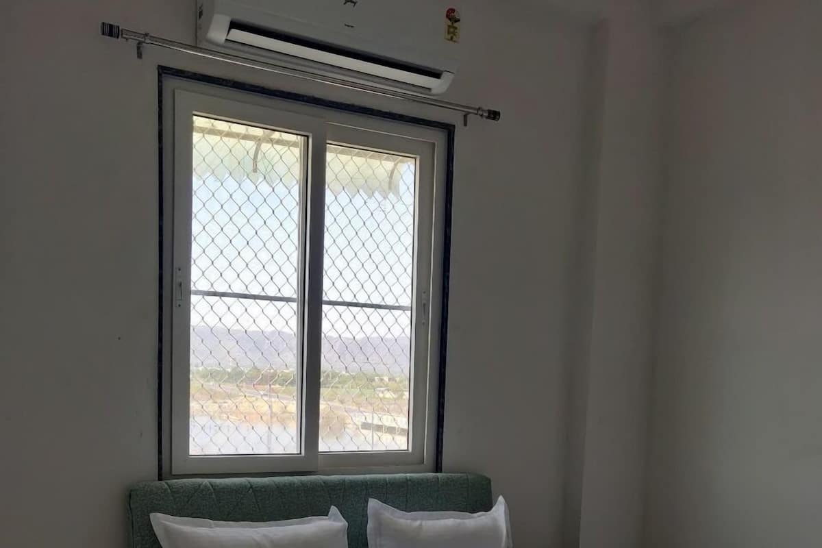 Ein Schlafzimmer mit Bett, Fenster mit Blick, Klimaanlage und einem kleinen Nachttisch.