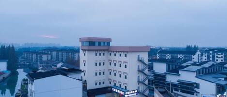 A multi-story building with a flat roof, a central entrance, and a parking area.