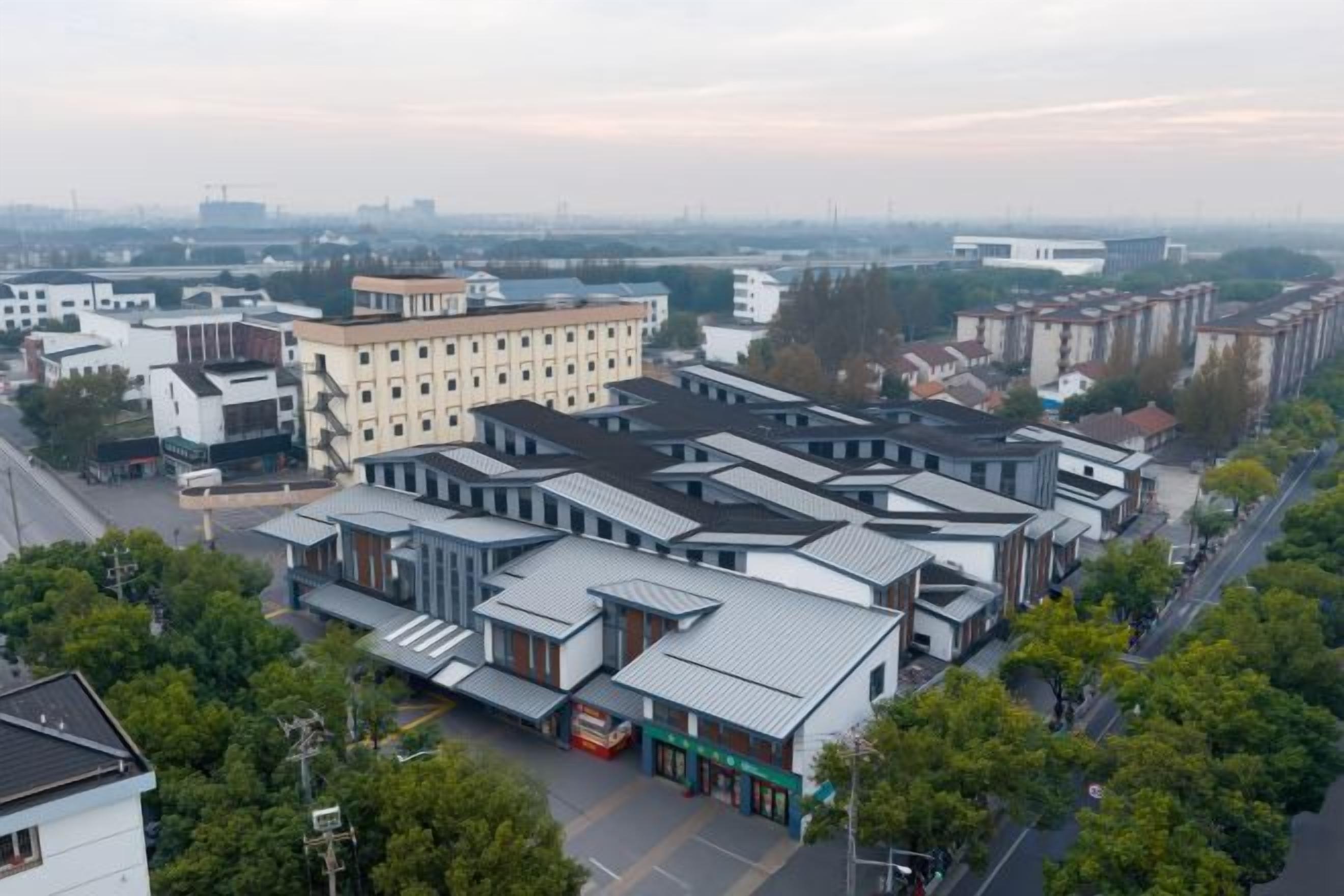 A commercial area with multiple buildings, including a large white building with a flat roof and several smaller structures with sloped roofs.