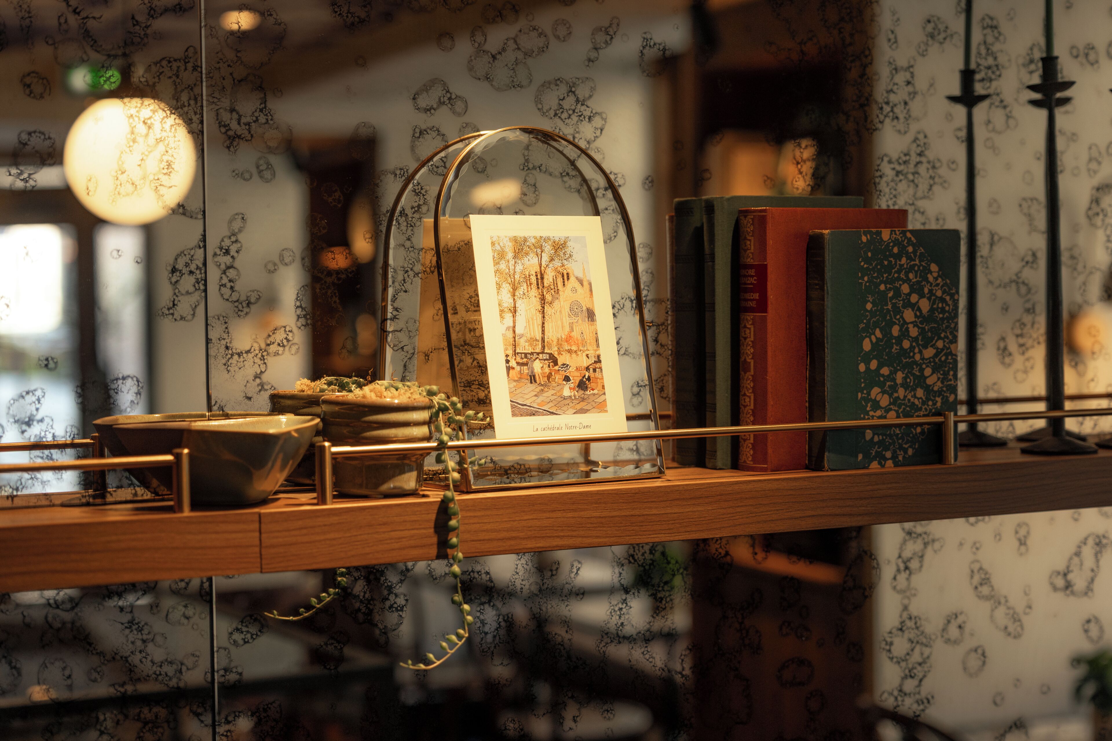 A shelf with a glass dome containing a framed picture, books, and a small bowl.