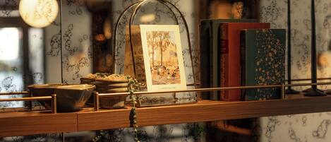 A shelf with a glass dome containing a framed picture, books, and a small bowl.