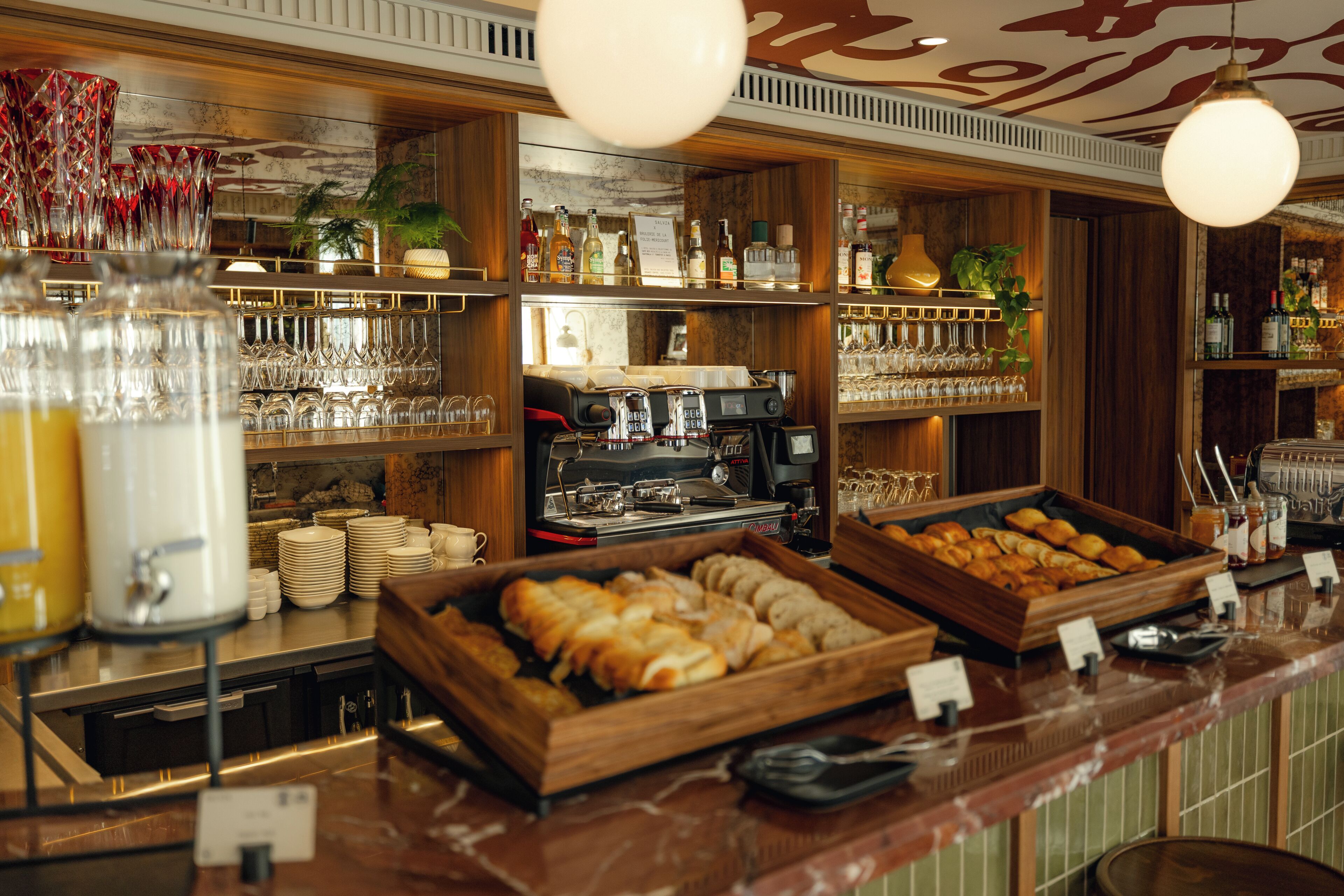 Un espace bar avec des étagères remplies de bouteilles, de verres et une machine à café.