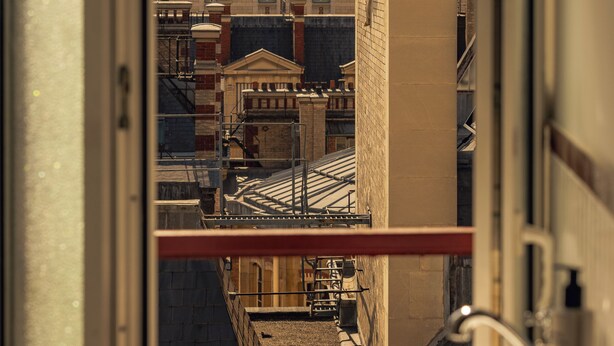 A view from a window of a building with a large white sink, a metal railing, and a glimpse of a cityscape with historical architecture. - SALVIA Paris (Paris)