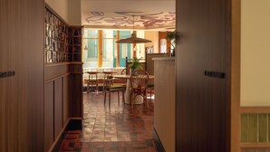 A hallway with patterned flooring, wooden walls, and a dining area with tables and chairs. - SALVIA Paris (Paris)