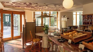 A dining area with a round table, chairs, a hanging light fixture, and a buffet counter with food items. - SALVIA Paris (Paris)