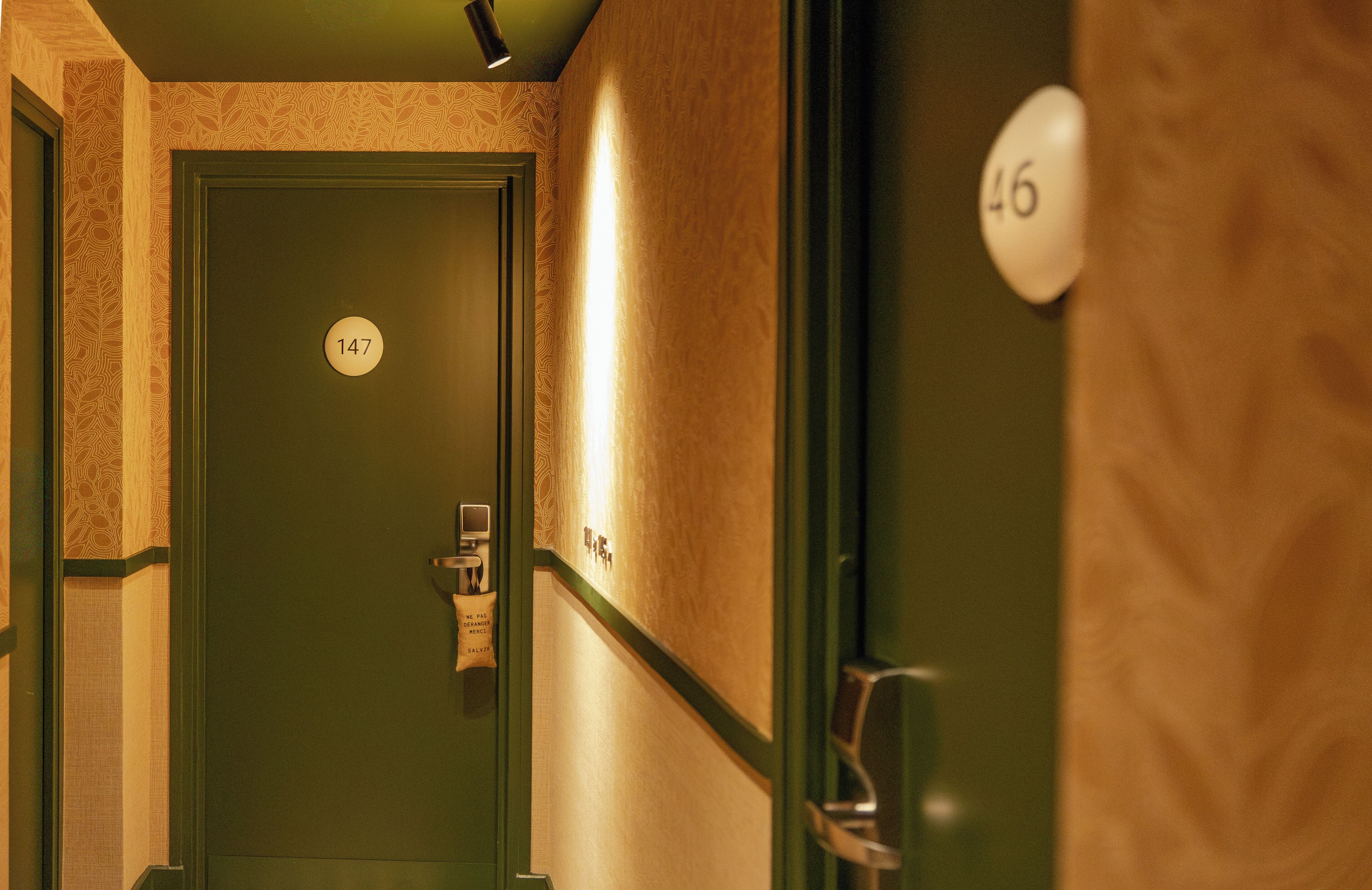 Passadís amb portes numerades 147 i 46, un llum penjada a la paret i un tirador de porta.