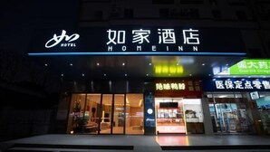 En hotellentrédörr med en skylt som visar texten ”Home Inn”.