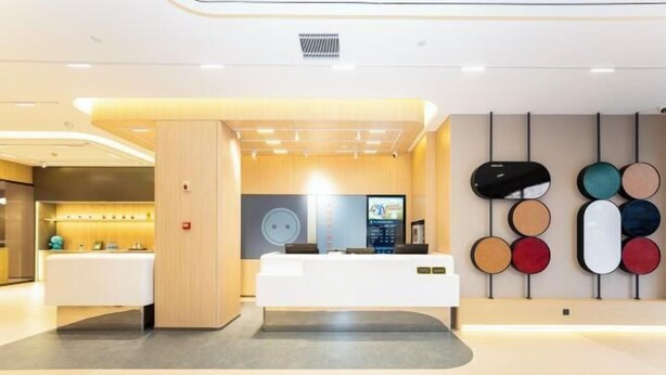 Ett modernt receptionsområde med en vit receptionsdisk, en digital skärm och en vägg med cirkelformade dekorativa element.
