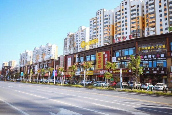 A street lined with multi-story buildings, each with various commercial establishments. - Homeinn · neo (Shanghai International Tourism Resort Xiuyan Road Subway Station) (Shanghai)