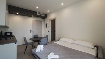 Una habitación de hotel con una cama, un escritorio con microondas, una silla y una mesita.