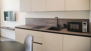 A modern kitchen with a built-in microwave, a sink, and a flat-screen TV mounted on the wall. - Residence Hotel Goldoni6 (Rimini)