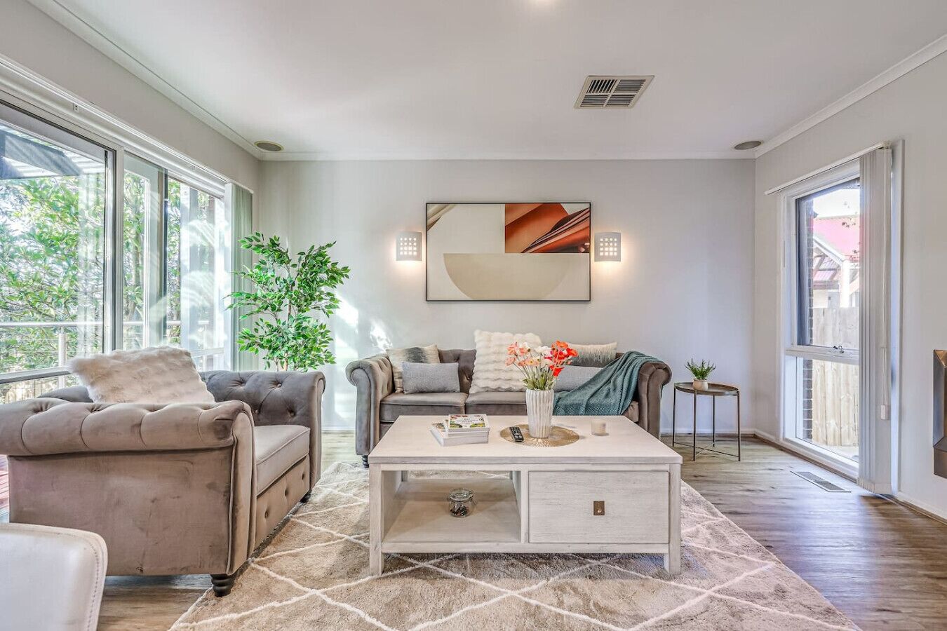 A living room with a sofa, armchairs, a coffee table, and a large window.