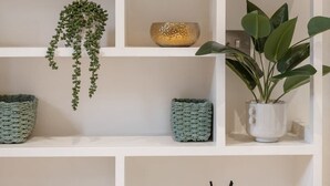 A white shelving unit with various decorative items including a hanging plant, a small bowl, a potted plant, and a bottle with a label. - New stylish 3-Bed Pimlico House near Big Ben (London)
