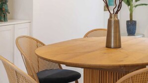 A round wooden dining table with four wicker chairs, a decorative mirror on the wall, and a vase with branches on the table. - New stylish 3-Bed Pimlico House near Big Ben (London)