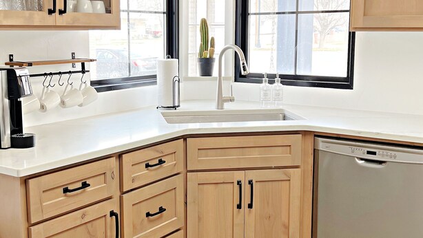 A kitchen with wooden cabinets, a dishwasher, and a window with a view of the outside.