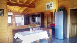 A wooden cabin interior with a dining table, cabinets, and a refrigerator.