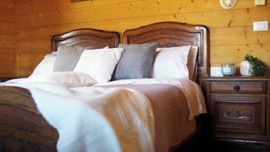 A wooden-paneled room with a bed featuring a wooden headboard, two nightstands, and a nightstand with a lamp.