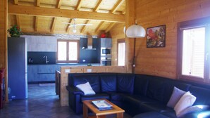 A spacious living area with a black leather sofa, wooden coffee table, and a kitchen in the background.