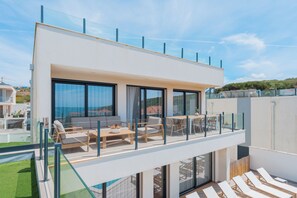 Un edificio moderno con balcón, mobiliario exterior y vistas al paisaje.