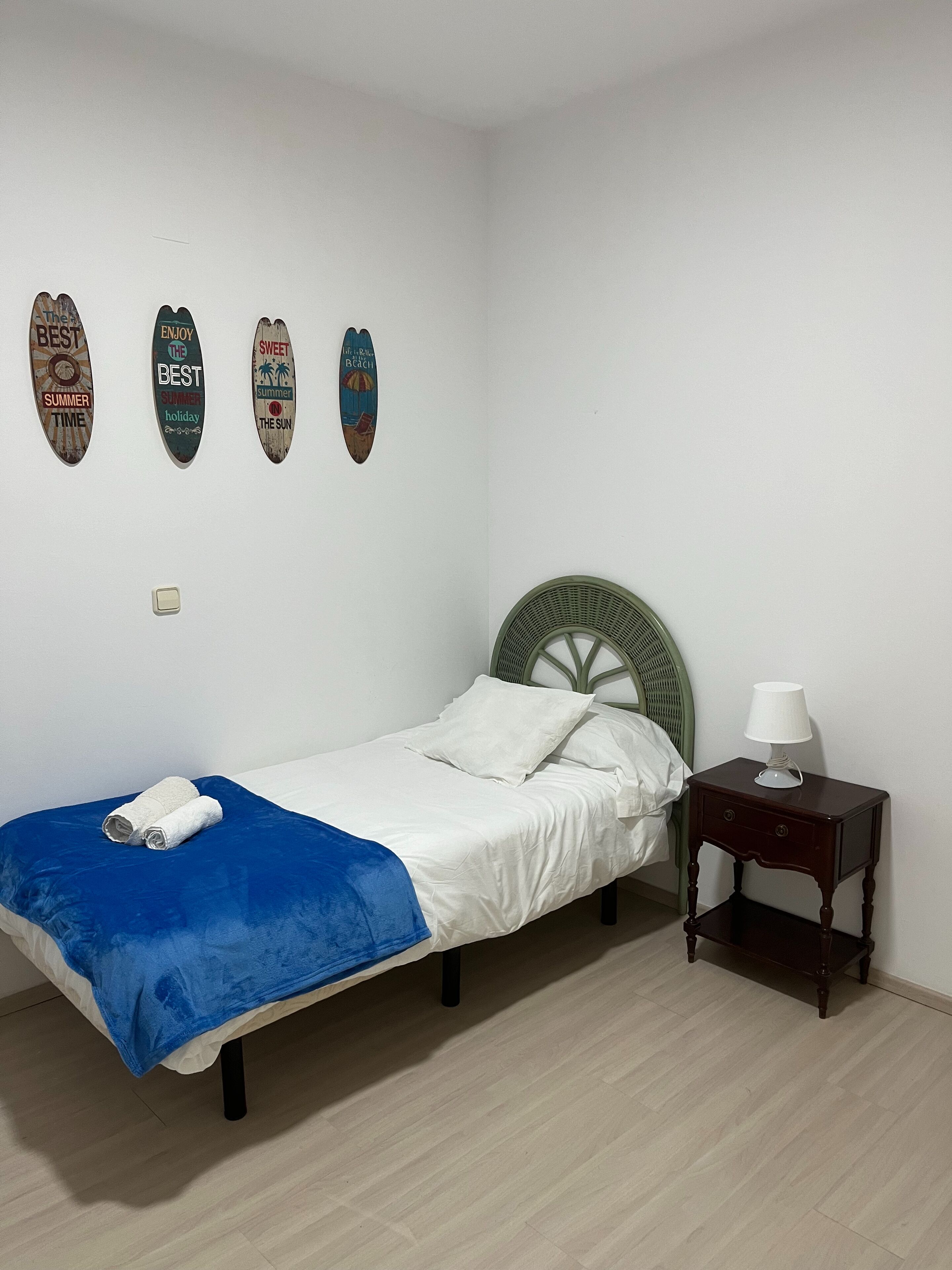 A bedroom with a single bed, a nightstand with a lamp, and three wall decorations.